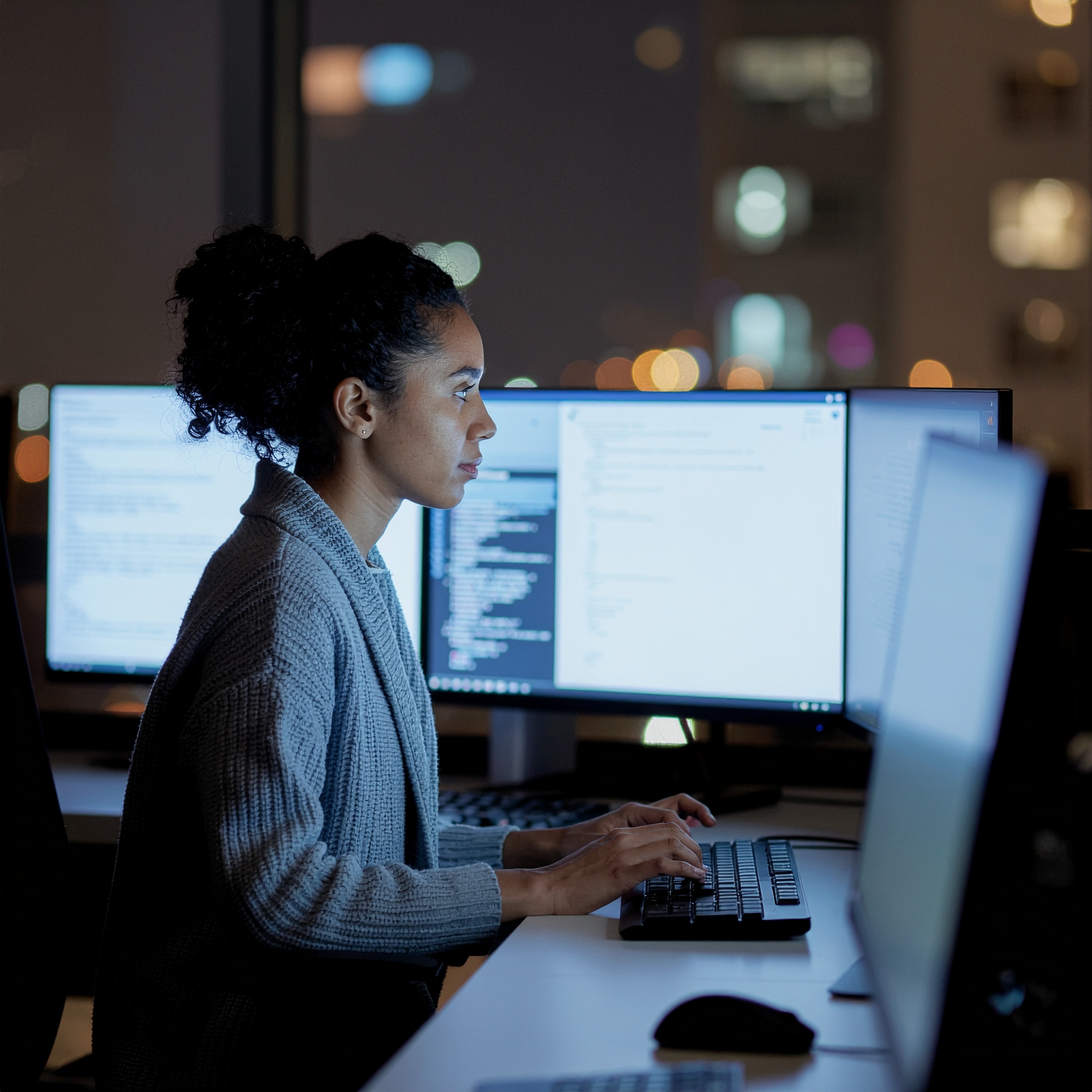 Focused Woman Coding in a Modern Office at Night